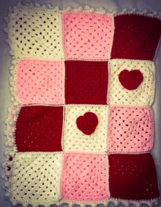 red white and pink Blanket made of Granny squares sewn together with hearts attached