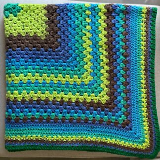 brown, blue, green striped blanket in Granny stitch folded twice laid on couch