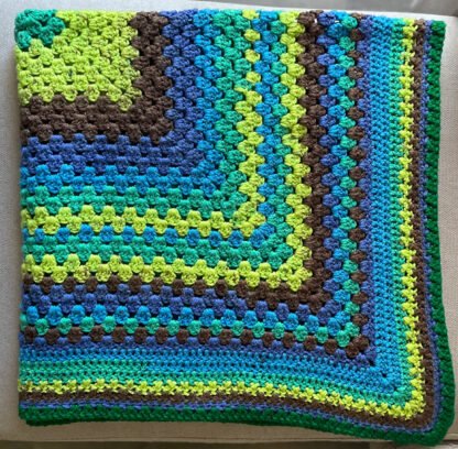 brown, blue, green striped blanket in Granny stitch folded twice laid on couch
