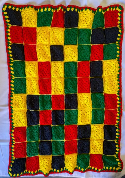 red, black, yellow granny square blanket laying flat - back of blanket