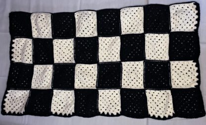 alternating black and white Granny squares sewn together into a blanket