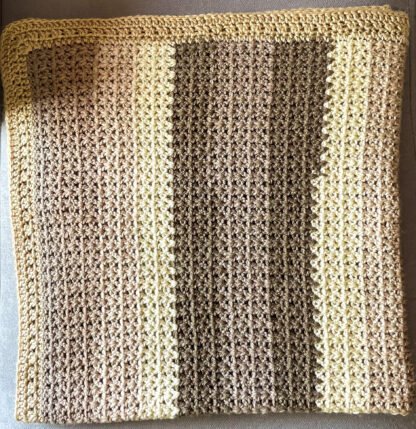 coffee and cream v-stitch crochet blanket folded in half twice laid on chaise lounge